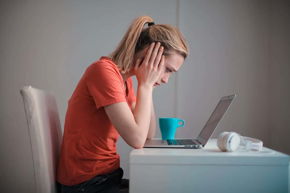 Woman on laptop with head in hands